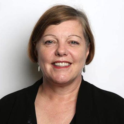 Sir Damon Buffini, Chair of the Queen Elizabeth Trust, smiling at the camera in a studio portrait.